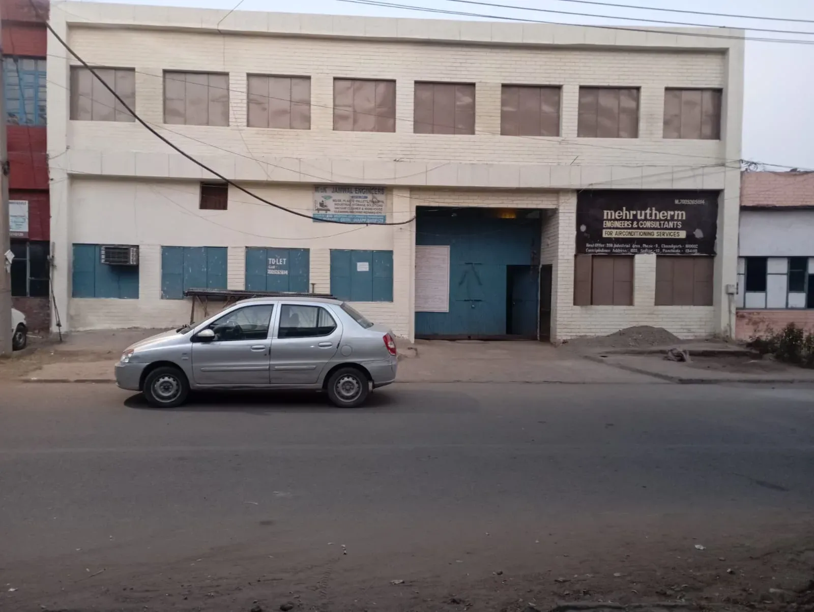 The white brick office building of Mehrutherm Engineers and Consultants in India, its painted sign advertising air conditioning services